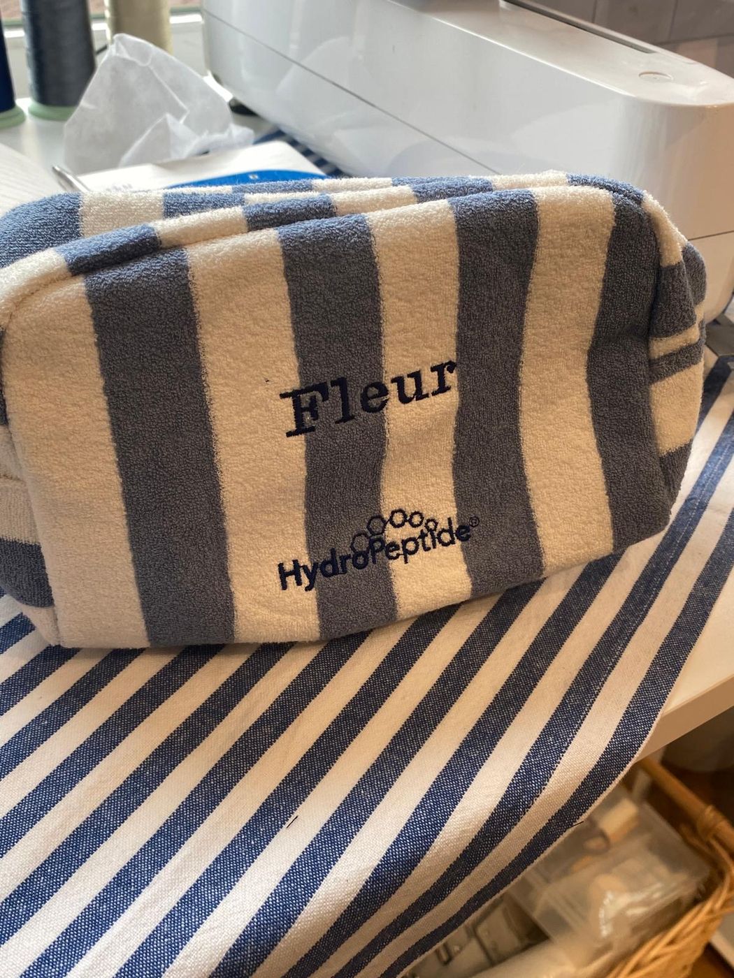 Geborduurde make-uppouch met de naam Fleur en het HydroPeptide-logo