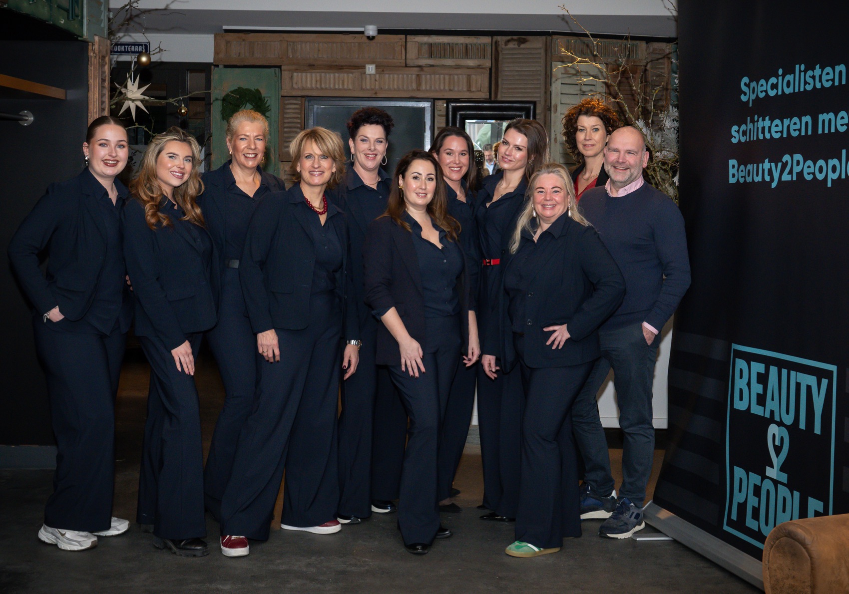 Het team van Beauty2People in donkerblauwe kleding voor de bedrijfsbanner